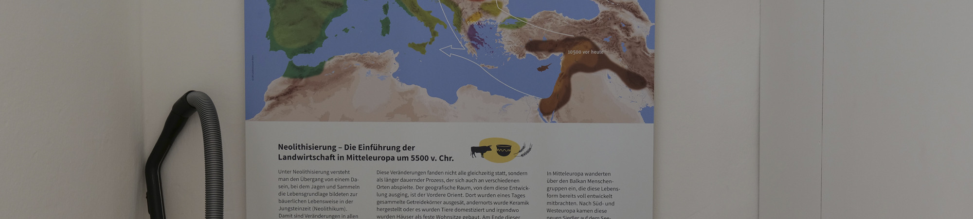 Staubsauger neben Schautafel -- Reinigungsutensilien verlassen zuletzt den Schauplatz.