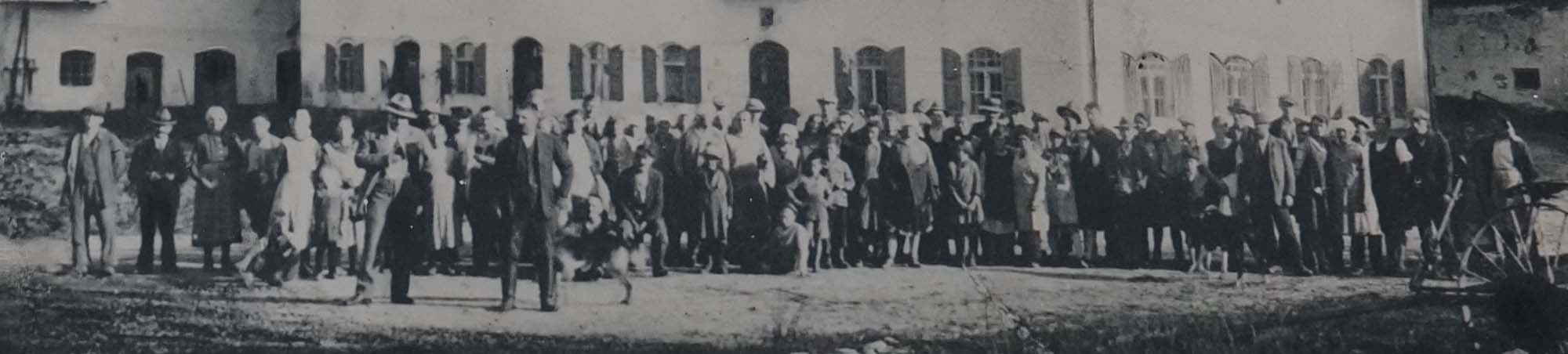 Menschengruppe vor einem unbekanntem Gehöft aus unbekanntem Anlass