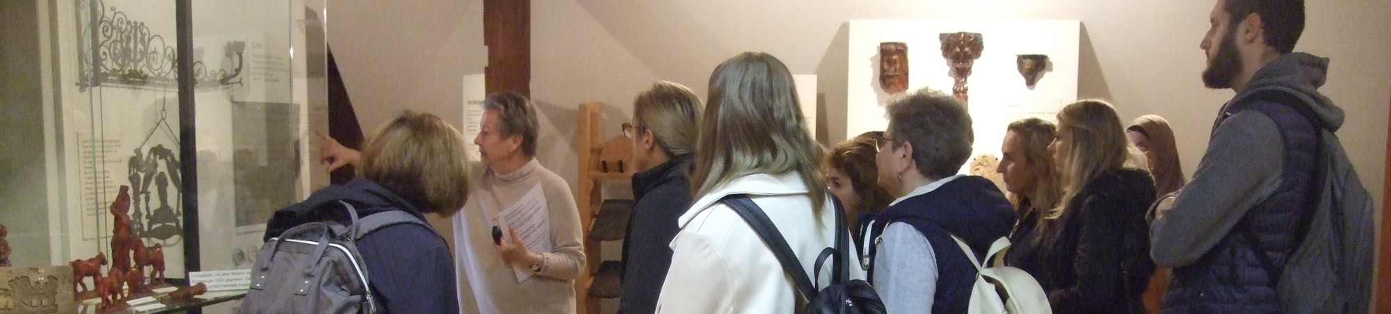 Die Teilnehmerinnen und Teilnehmer betrachten alte Zunftzeichen und eine Vitrine mit Lebzelten.