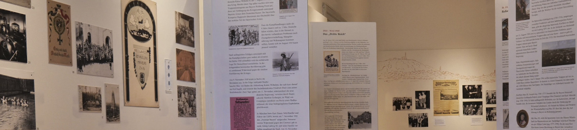 Entlang eines roten Zeitstrahls sind beidseitig Bilder, Grafiken und Texttafeln aufgereiht. Blick in Richtung Stadterhebung.