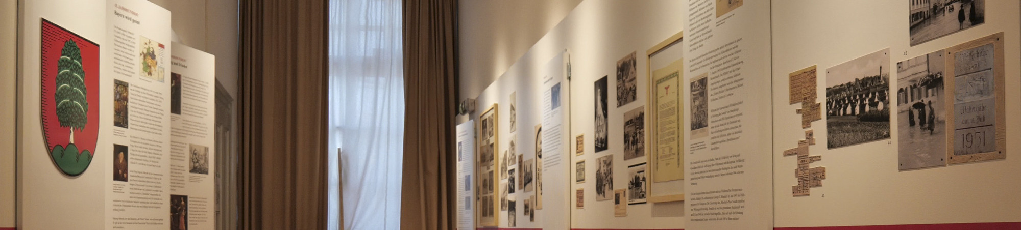 Entlang eines roten Zeitstrahls sind beidseitig Bilder, Grafiken und Texttafeln aufgereiht. Blick in richtung Fenster.