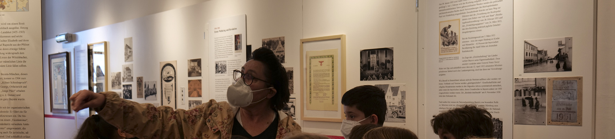 Lehrerin zeigt auf ein Ausstellungsobjekt und erklärt