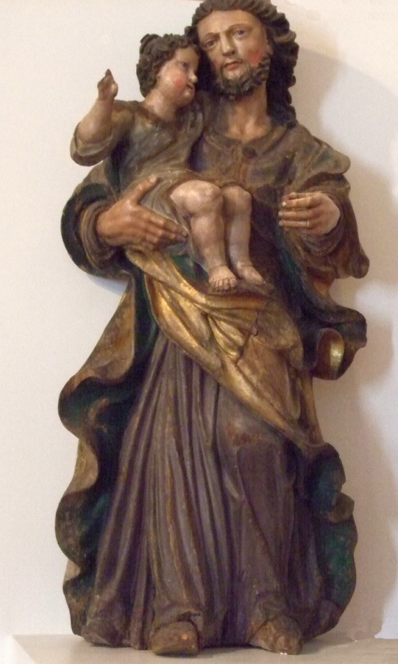 Ein Mann trägt auf rechtem Arm den Christuskaben, der die rechte zur Segnungsgeste erhoben hat.