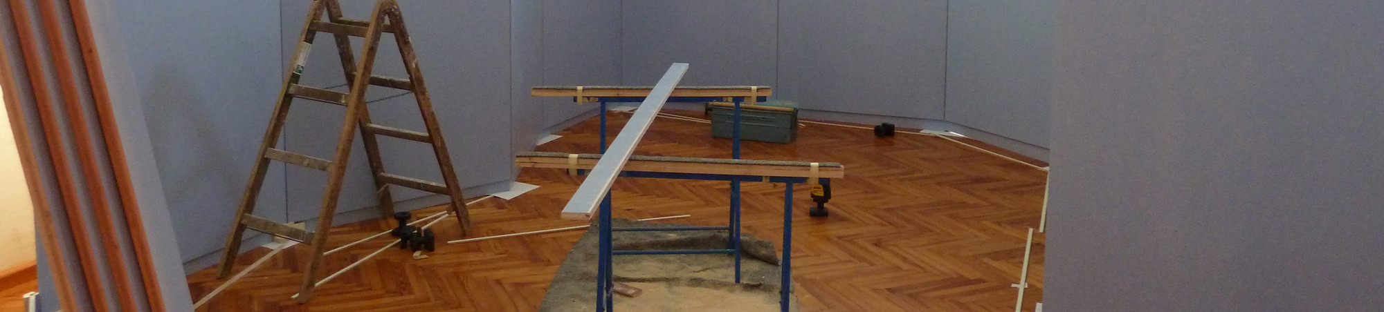 Ausstellungswände werden zugeschnitten, nach Plan aufgestellt und gestrichen.