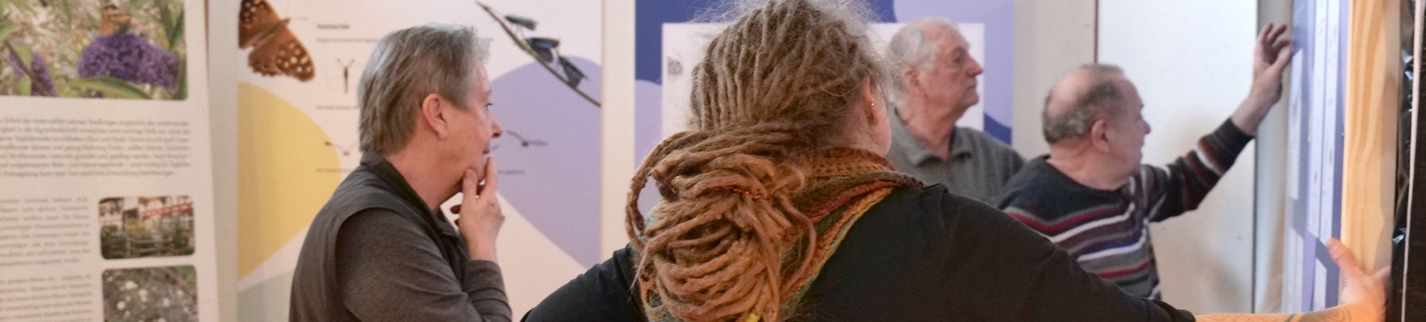 Vier Personen erarbeiten eine Lösung zur Befestigung von zwei Ausstellungsplatten.