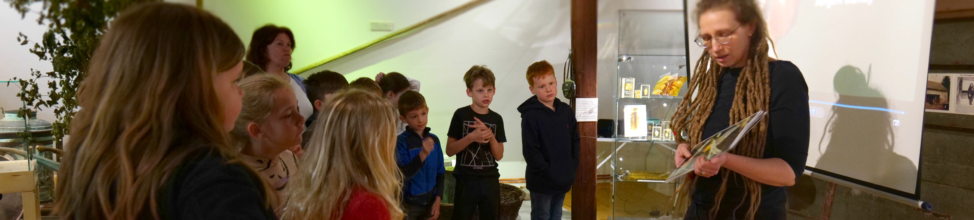 Biologin spricht mit den Kindern. Sie hat als unterst&uuml;tzendes Unterrichtsmittel A4-Bl&auml;tter mit Abbildungen aus dem Film.