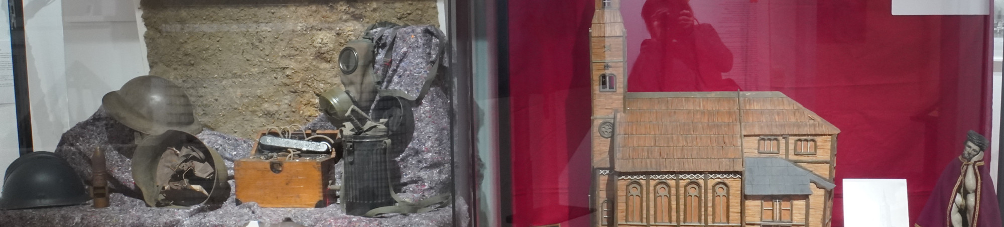 Von links nach rechts: drei Stahlhelme (Englisch, Französich, Deutsch) Feldtelefon, Gasmasken, Streichholzmodell alte Liebfrauenkirche, kleine Kirchenplastik